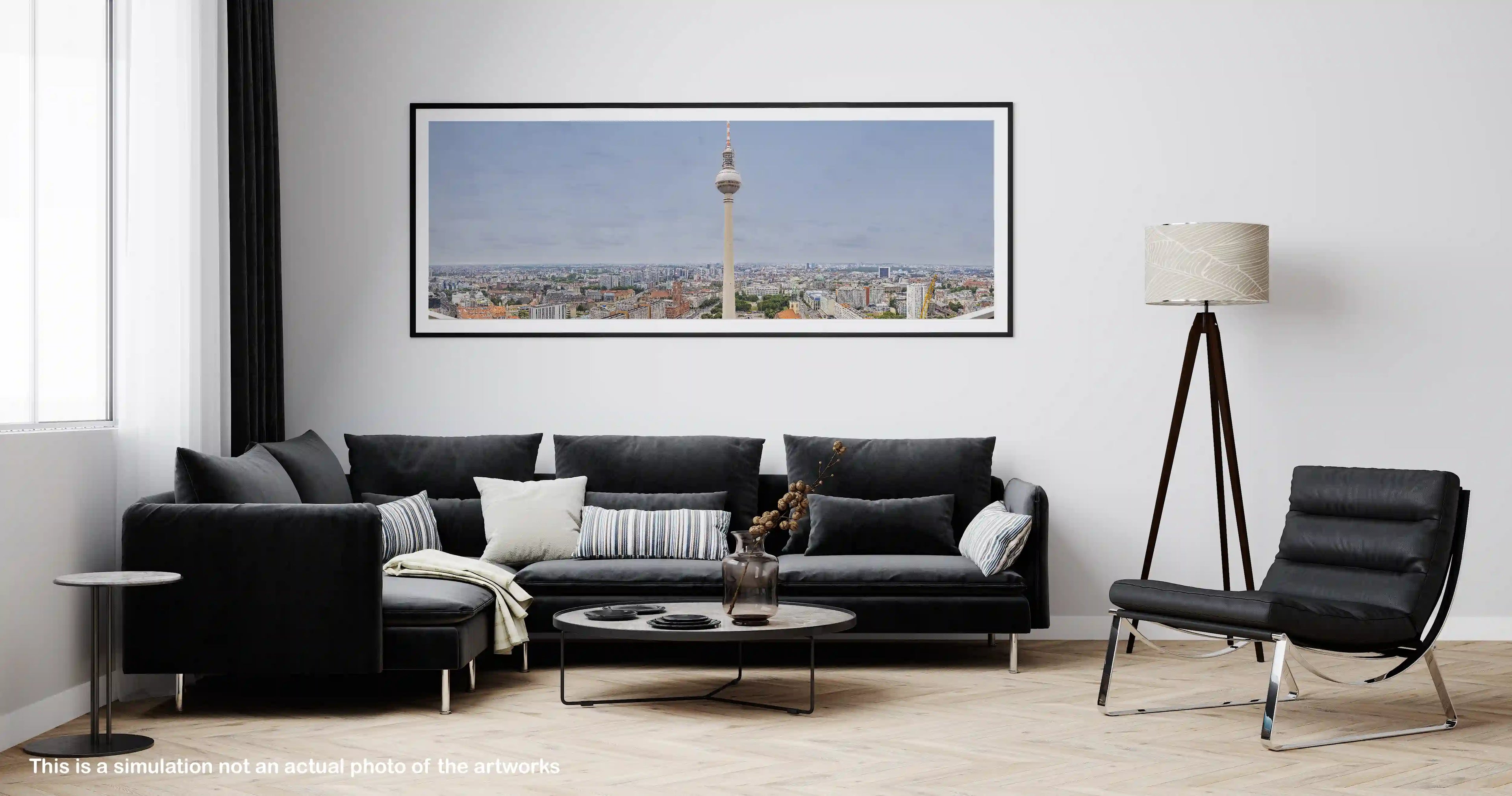 Modern living room with a black sectional sofa, armchair, and framed picture of a cityscape.