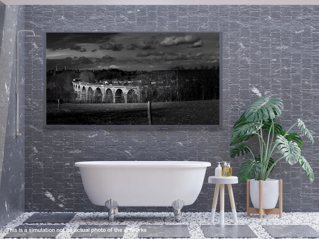 Bathroom interior with a freestanding bathtub, plant, and framed artwork on a textured wall.