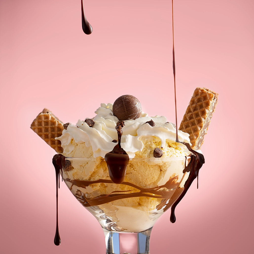 Thumbnail of a luxurious moment as rich, velvety chocolate sauce cascades over a sumptuous bowl of vanilla ice cream, crowned with whipped cream and accented by crispy wafer sticks.