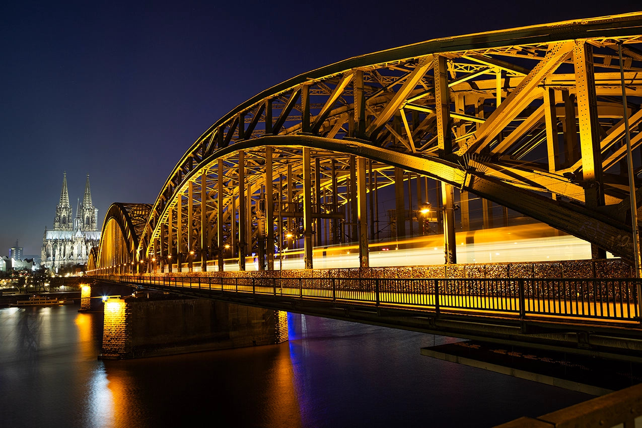 Bridge illuminated at night with a cathedral in the background