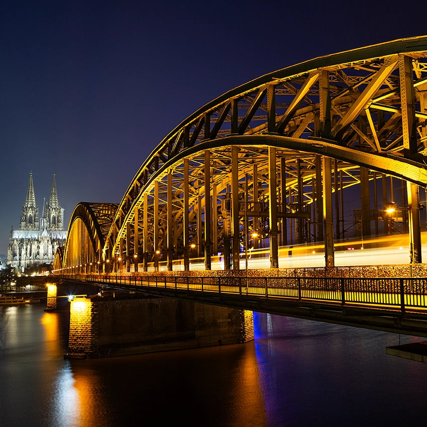  illuminated bridge over a body of water with a cathedral in the background