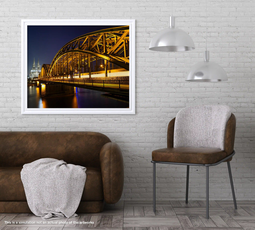 Framed photograph of a bridge over water in an interior setting with a brown sofa and chair.