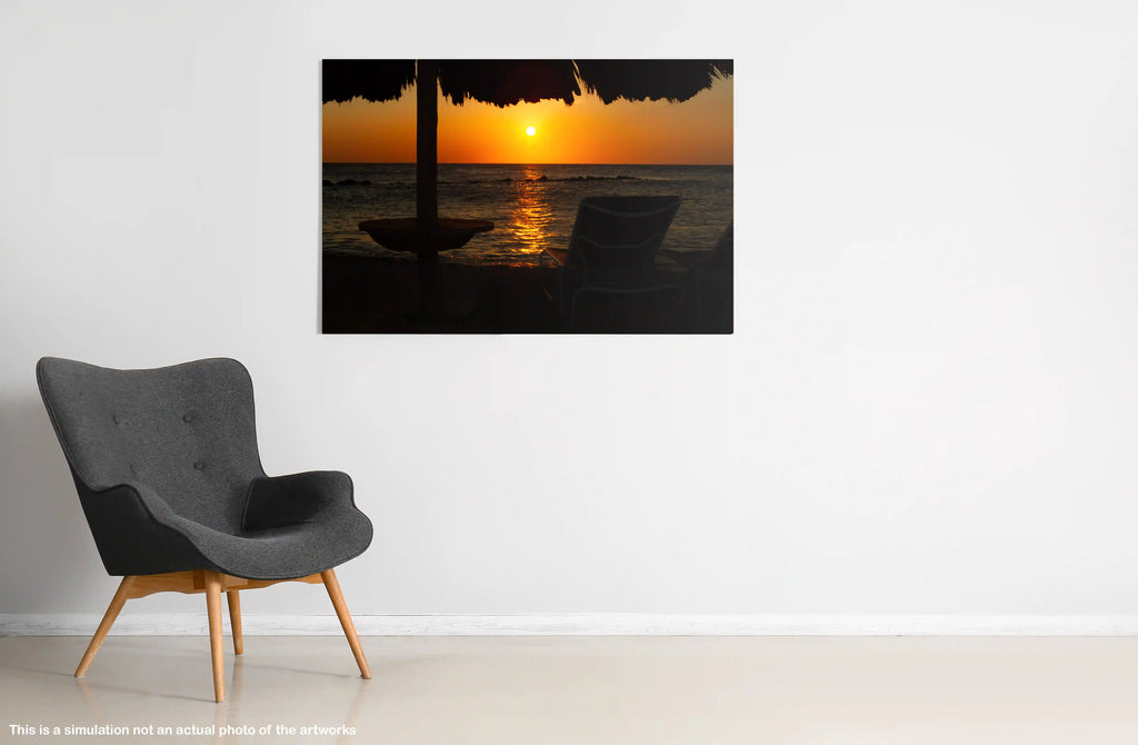 Gray armchair in a room with a large wall-mounted picture of a sunset over water.