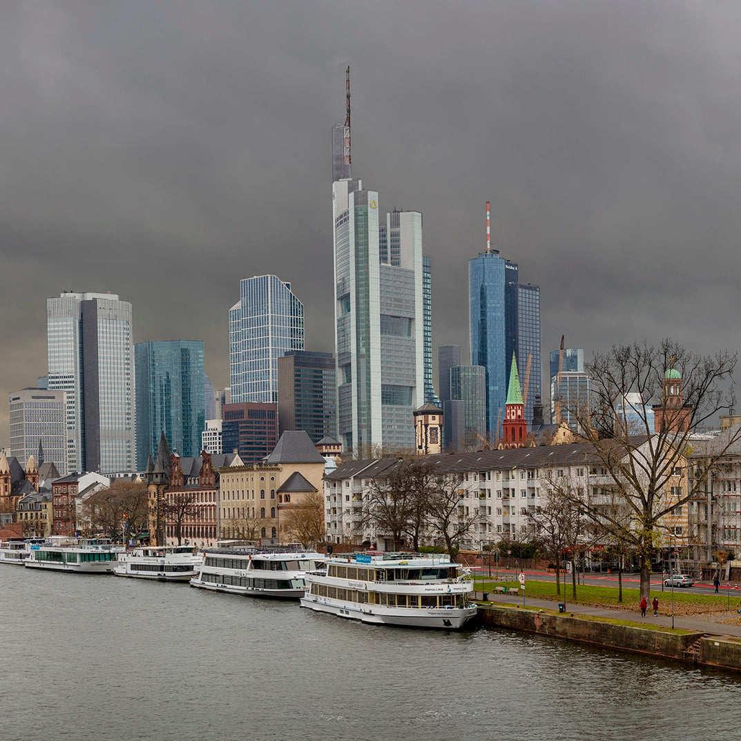 Thumbnail of panoramic view of Frankfurt. The towering skyscrapers of the financial district rise dramatically into the stormy sky, while the Gothic spires of the Frankfurt Cathedral remind us of the city’s deep historical roots