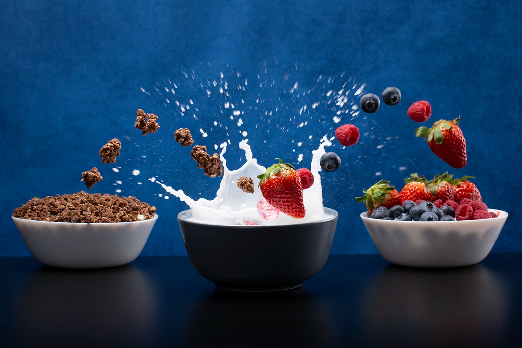 Bowl of cereal with milk and fruit against a blue background
