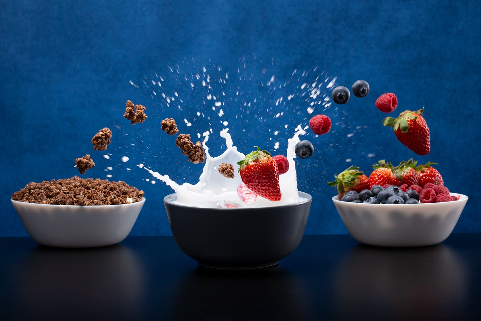 Bowl of cereal with milk and fruit against a blue background
