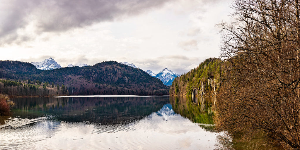 Lake surrounded by mountains and trees on a cloudy day