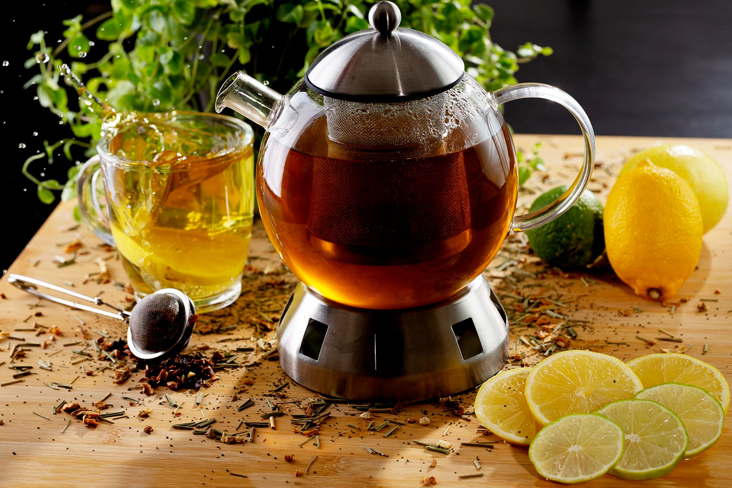 Tea set with a teapot, glass mug, and lemon slices on a wooden surface.