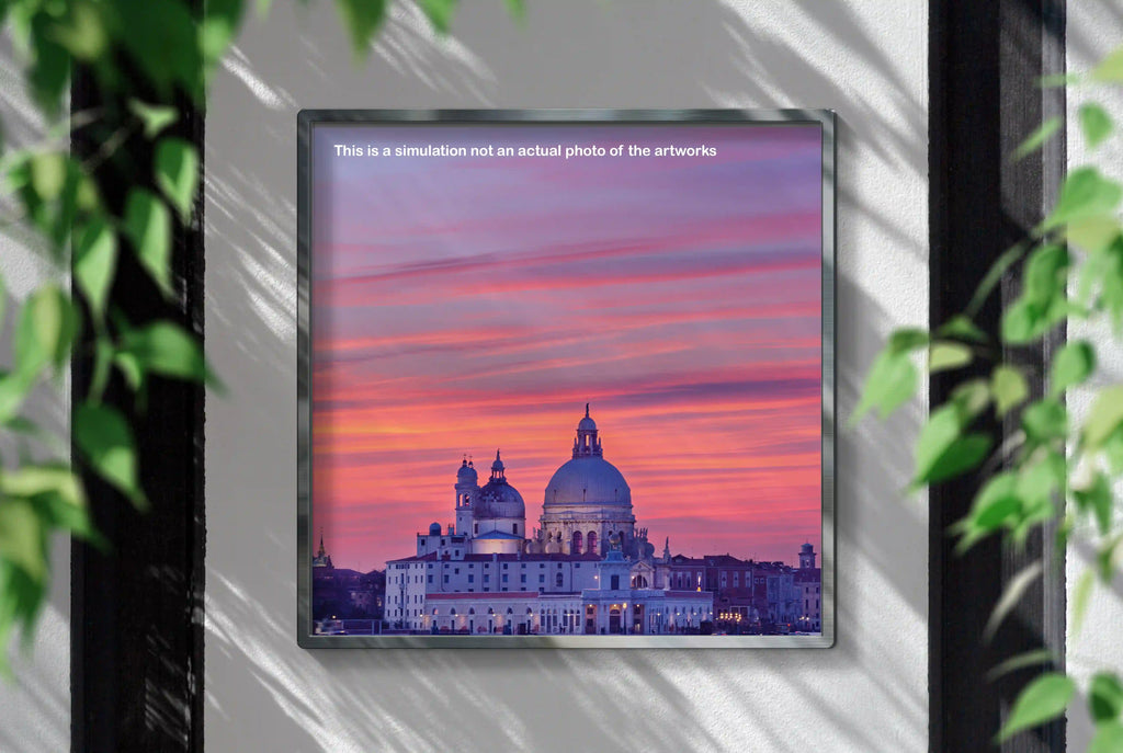 Framed artwork of a cityscape with a pink and purple sky, displayed on a wall.