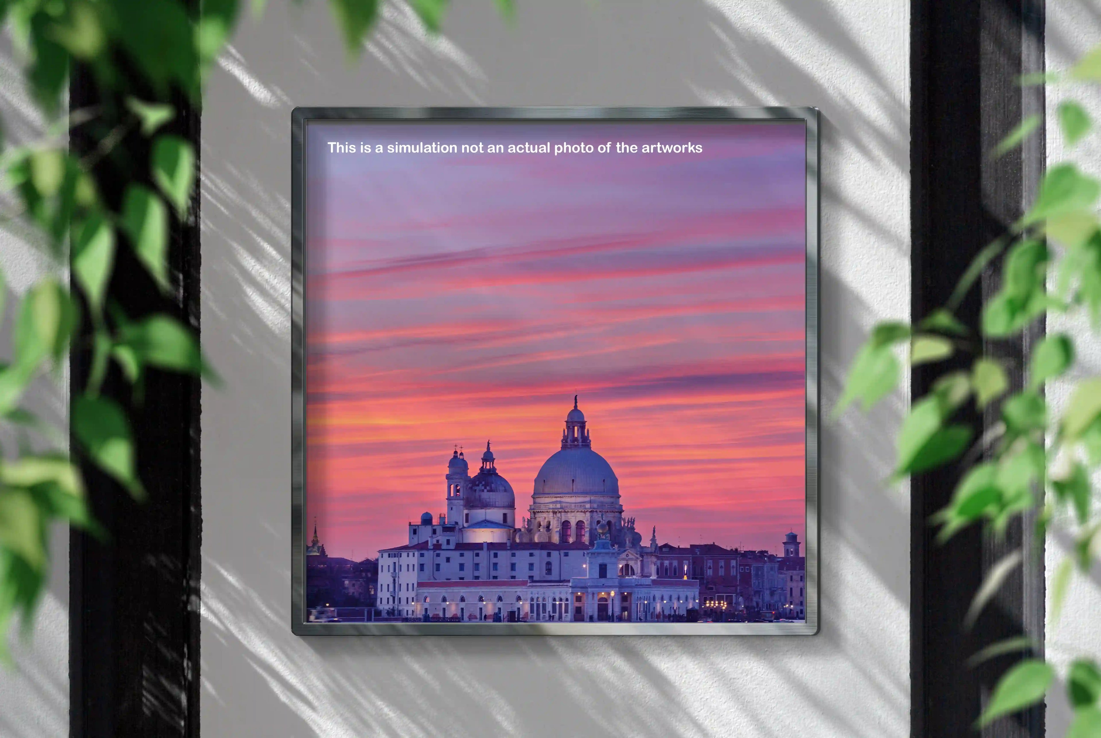 Framed artwork of a cityscape with a pink and purple sky, displayed on a wall.