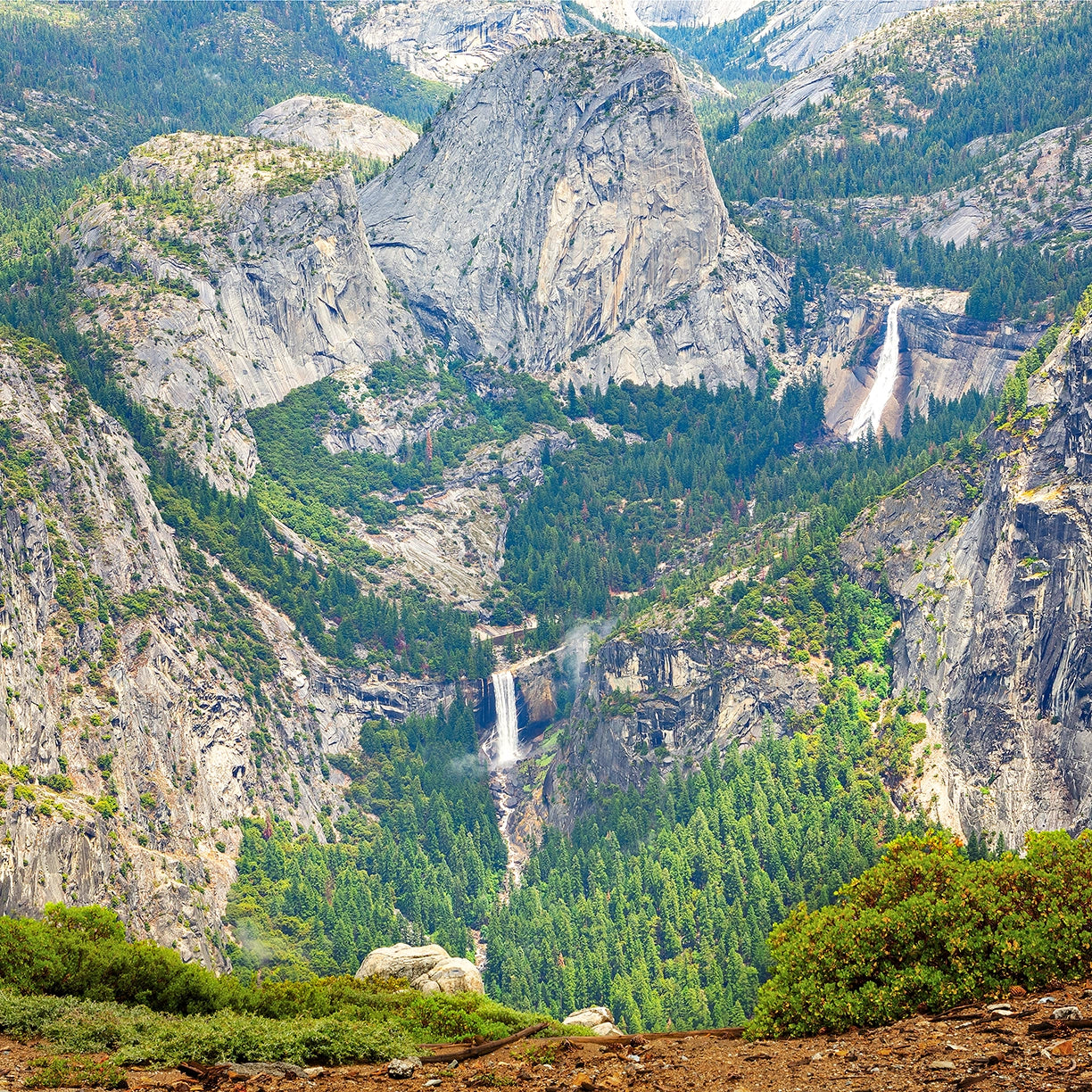 Valley view with mountains, trees, and a waterfall in Yosemite National Park.